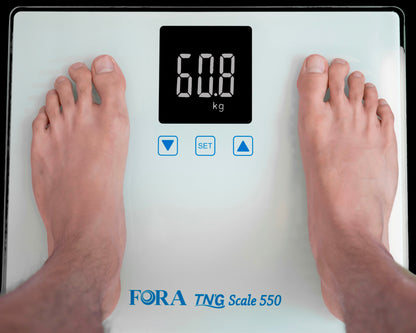 Person standing on FORA TN’G Scale 550 digital Bluetooth weight scale, LCD display showing 60.8 kg measurement.